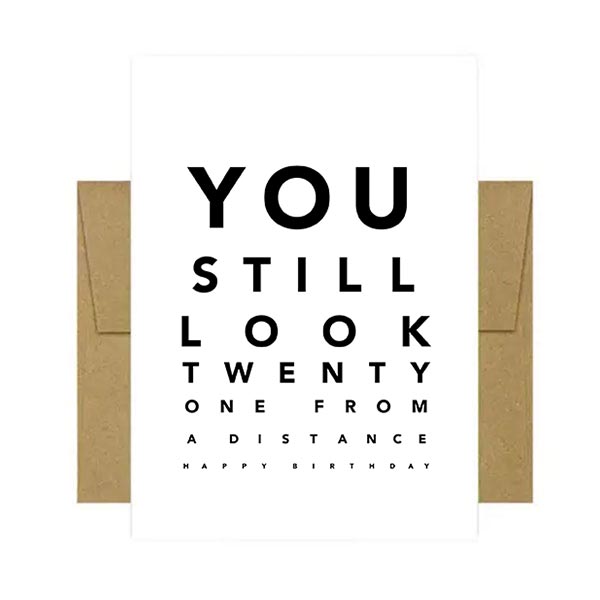 Greeting card with text 'You still look twenty one from a distance' on a white background with brown envelope.